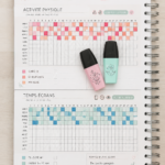Femme souriante prenant des notes dans un cahier, représentant le suivi de sa vie avec plaisir.